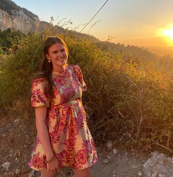 Jonge vrouw in een kleurrijke jurk bij zonsondergang in een bergachtig landschap